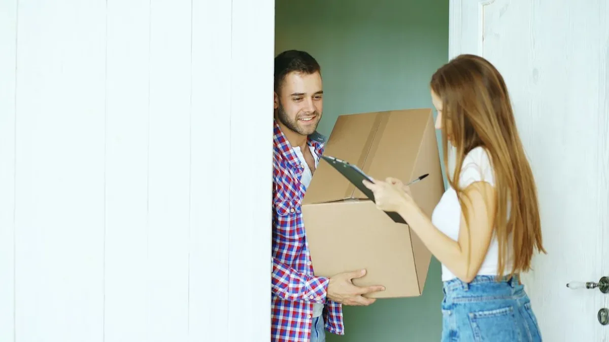 Colis en carton posé devant une porte d'entrée