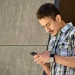 personne devant une consigne à colis consultant son smartphone