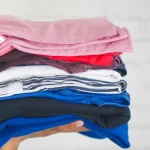 Vêtements de seconde main pliés sur un lit, prêts à être vendus