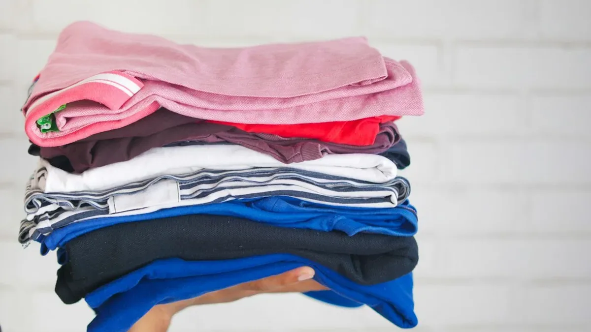 Vêtements de seconde main pliés sur un lit, prêts à être vendus